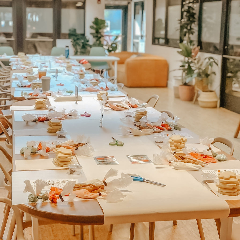 Long table set up with cookie decorating items, including cookies and frosting.